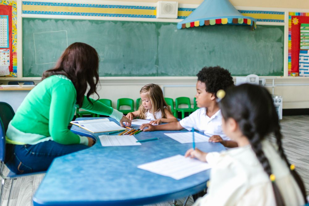 Teacher helping preschool children learn together at a classroom table