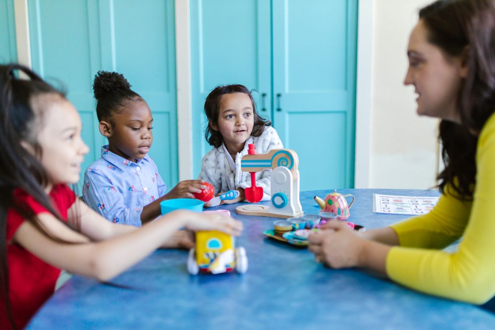 Two young children playing with colorful toys at a classroom table