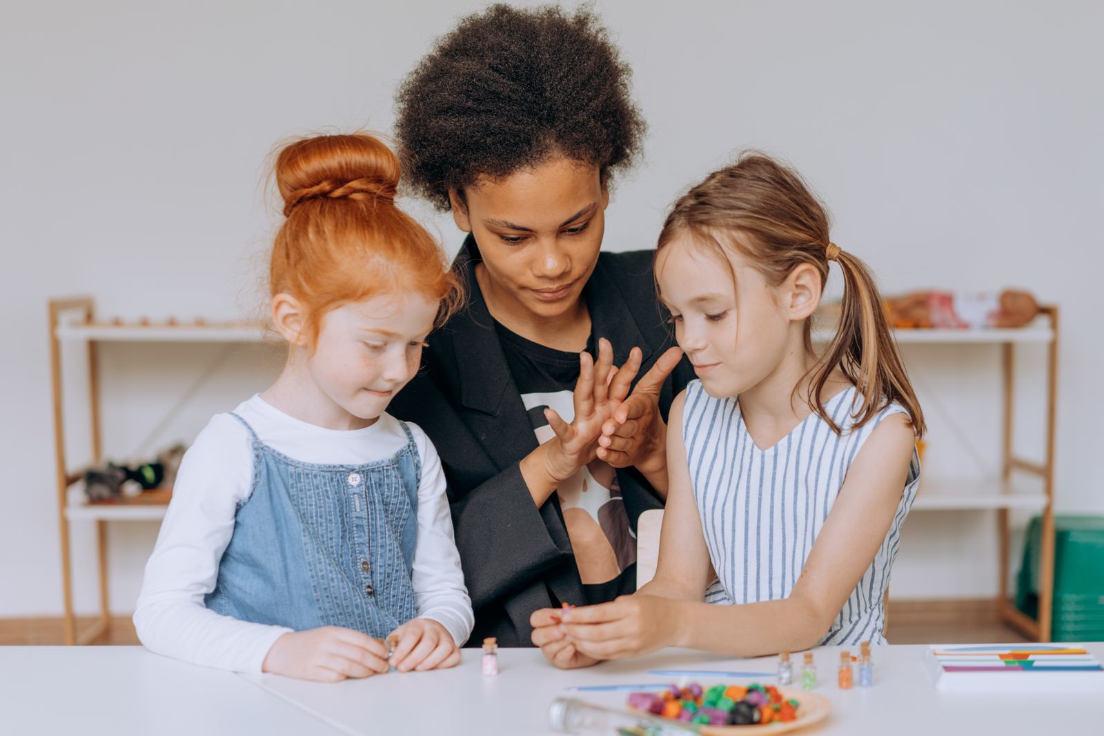 Teacher guiding two young girls through a hands-on activity